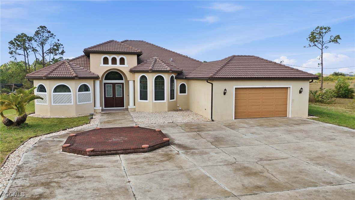Front elevation of the Mediterranean villa in daylight, showing the tile roof, arched entry, and three-car garage