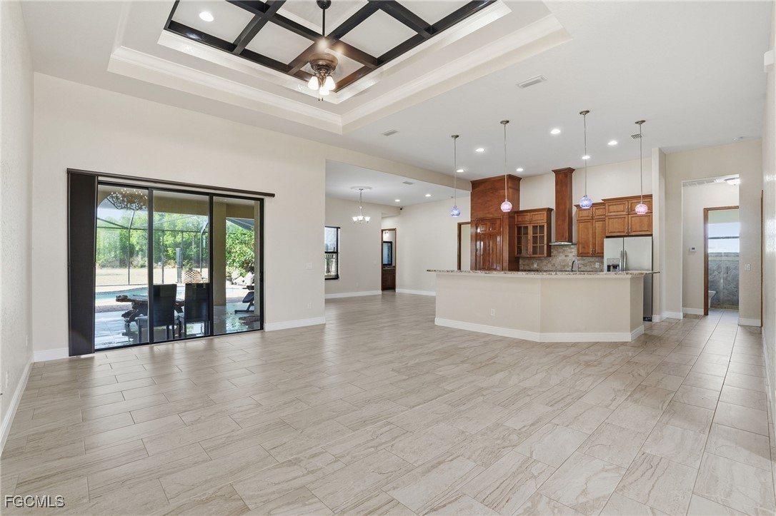 Open great room with a coffered lattice ceiling, sliders to the screened lanai, and the kitchen island visible on the right