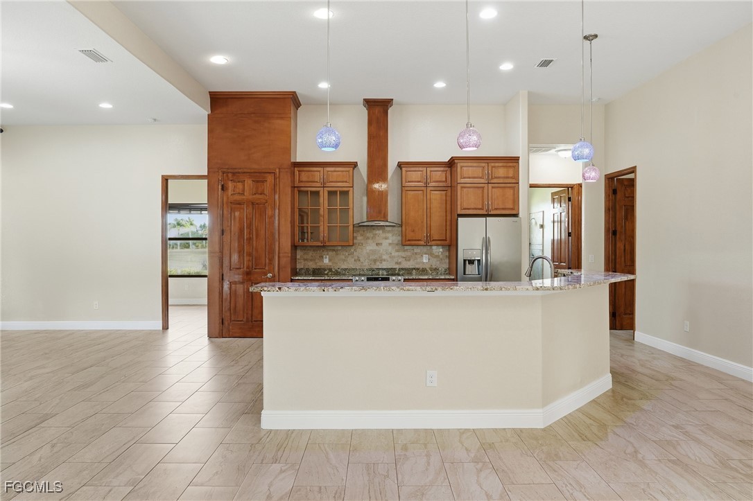 Kitchen with maple cabinetry, granite-topped island, pendant lights, and stainless appliances
