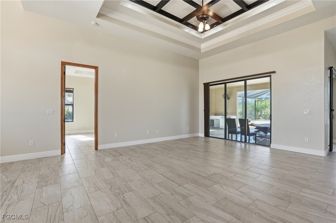 Primary bedroom with a coffered ceiling, sliders to the lanai, and double doors leading to the ensuite bath